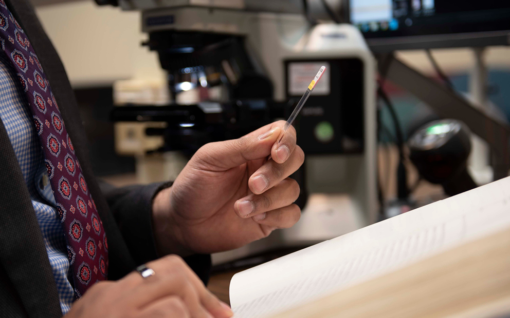 Man holding test strip microscope in background