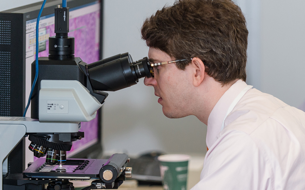 man in lab looking into a microscope