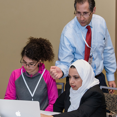 Two young women being mentored as they work on a computer