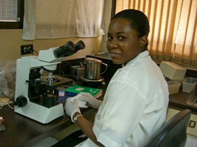 Haiti staff at microscope smiling at the camera