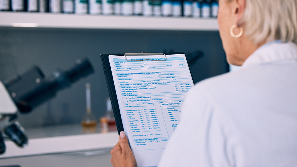 woman in laboratory looking down at clipboard