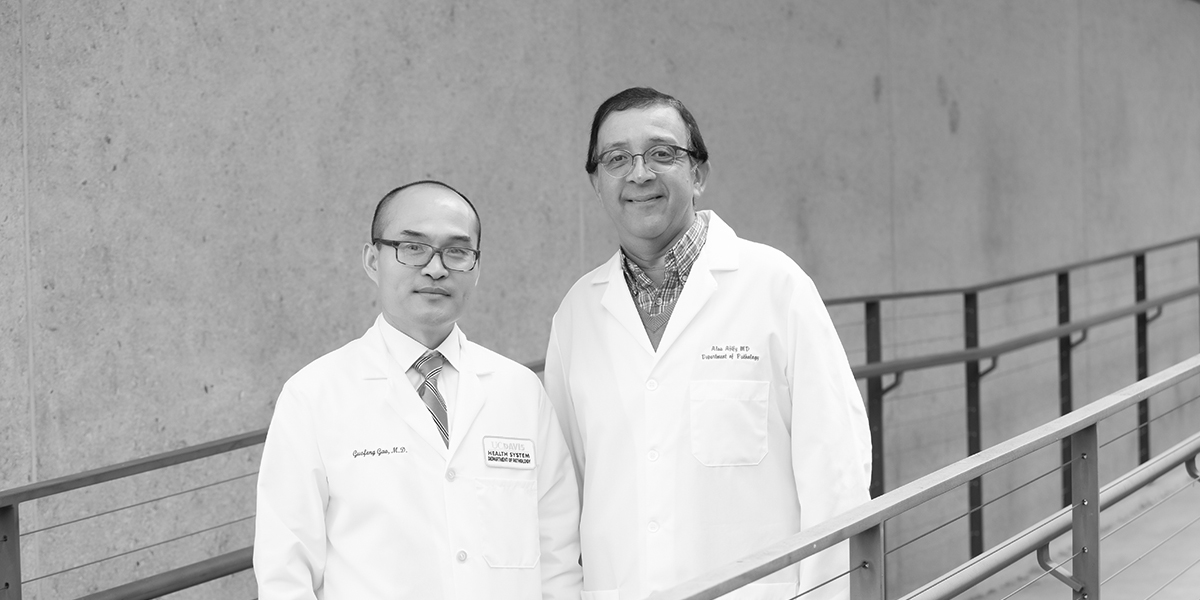 Two men in lab coats smiling at camera